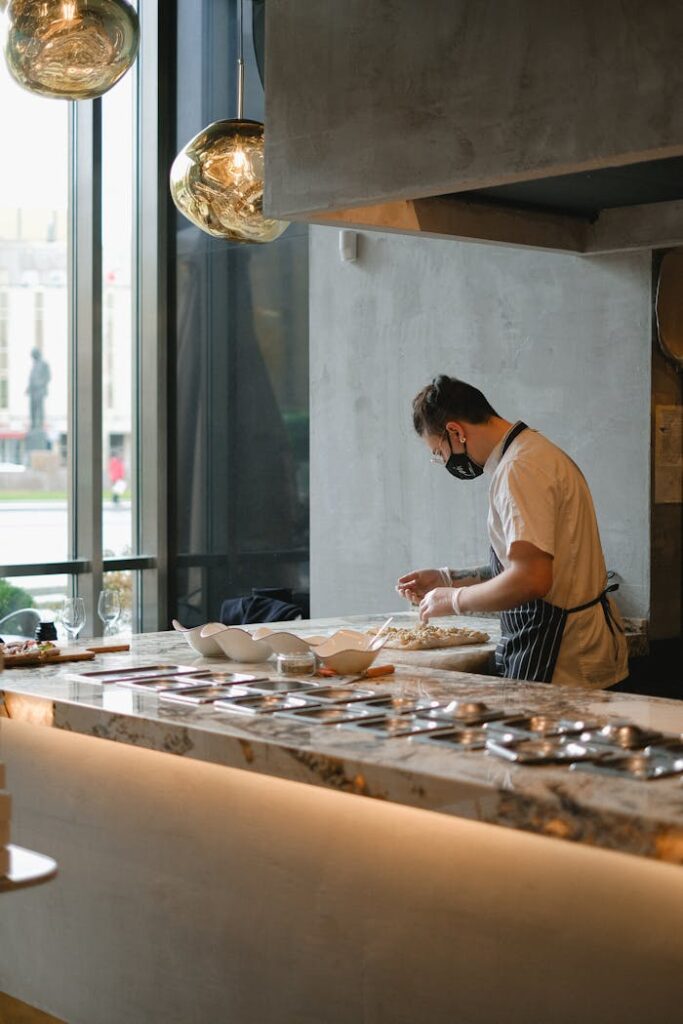 A chef wearing an apron meticulously prepares food in a modern kitchen setting, showcasing culinary skills.